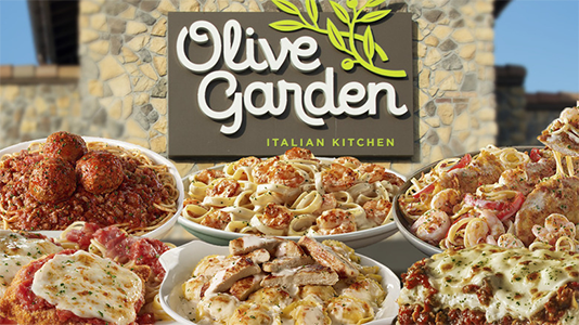 Image of Olive Garden Restaurant with various meals from the menu in front of it.