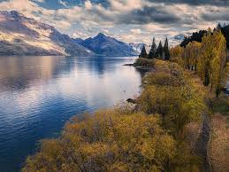 Large blue lake surrounded by trees with autumn leaves