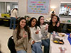Hadasyah, Gen, Maria, and Milla smiling and holding peace signs up at their senior thankgiving feast.