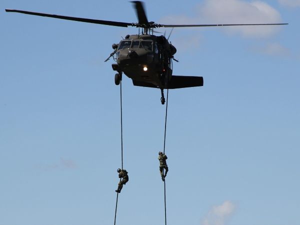 Blackhawk helicopter with soldiers sliding down ropes