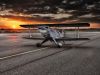 JSmall airplane parked in front of a sunset