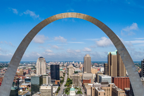 Photo of the Gateway Arch and the St. Louis skyline reflected in the Mississippi River at sunset.